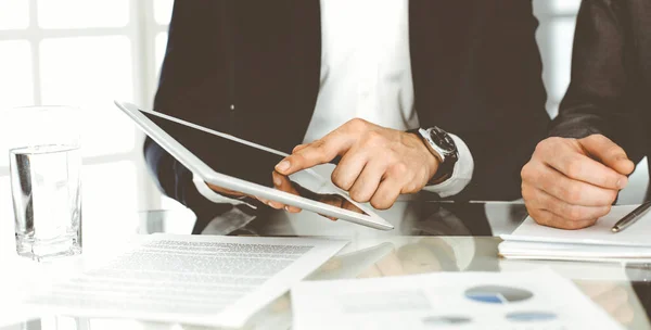 Geschäftsleute nutzen Tablet-Computer, während sie gemeinsam im modernen Büro arbeiten. Unbekannter Geschäftsmann sitzt mit seinem Kollegen oder Partner am Schreibtisch. Teamwork und Partnerschaftskonzept — Stockfoto