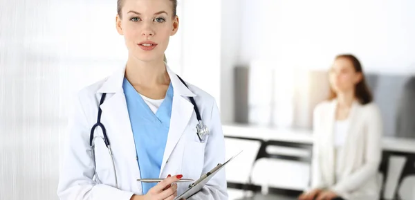 Mujer - el médico está utilizando portapapeles para llenar el formulario de registro de historial de medicamentos en la clínica soleada en el fondo del paciente — Foto de Stock