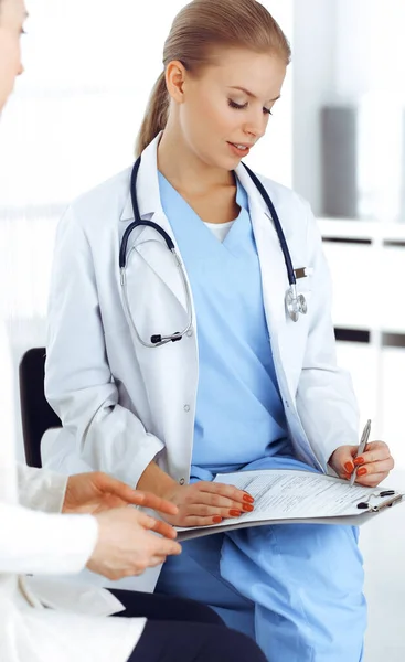 Woman - doctor consults her female patient while using clipboard and medication history record. Medicine concept — Stock Photo, Image