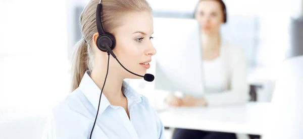 Mujer rubia operador de llamadas está utilizando la computadora y auriculares para consultar a los clientes en línea. Grupo de personas diversas que trabajan como ocupación de servicio al cliente. Concepto empresarial — Foto de Stock