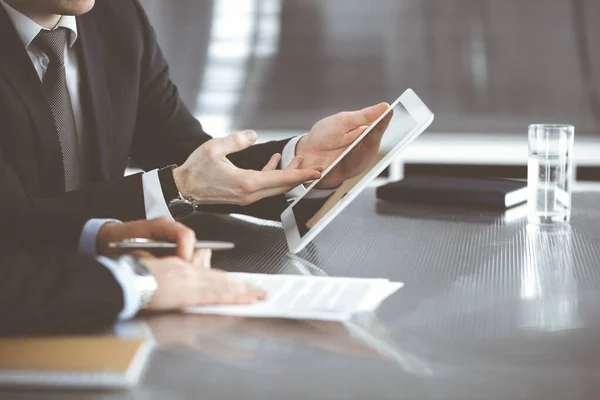 Des hommes d'affaires inconnus utilisent une tablette informatique et travaillent ensemble au bureau en verre dans un bureau moderne, en gros plan. Travail d'équipe et concept de partenariat — Photo