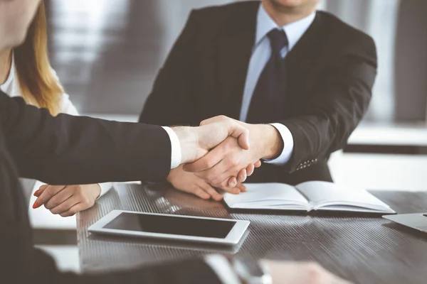 Onbekende zakenmannen schudden handen boven het glazen bureau in een modern kantoor, close-up. Onbekende zakenmensen bij een ontmoeting. Teamwork, partnerschap en handdruk concept — Stockfoto