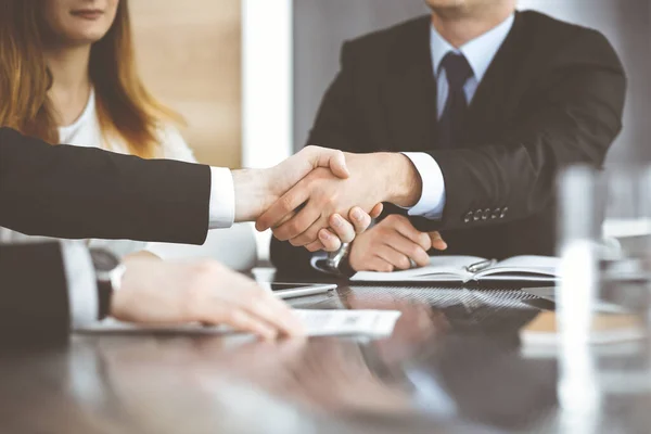 Onbekende zakenmannen schudden handen boven het glazen bureau in een modern kantoor, close-up. Onbekende zakenmensen bij een ontmoeting. Teamwork, partnerschap en handdruk concept — Stockfoto