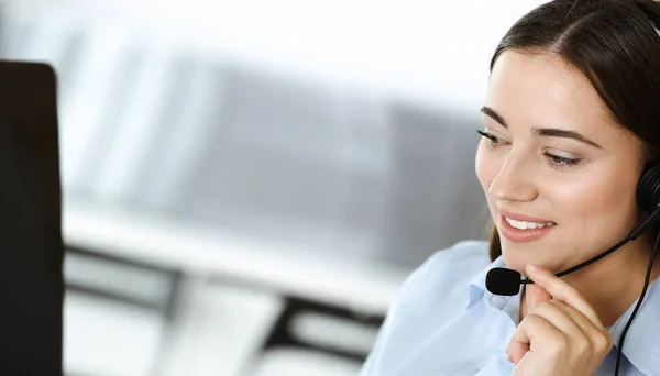 Morena representante de servicio al cliente femenino en un auricular está consultando a los clientes en línea. Centro de llamadas y concepto de gente de negocios — Foto de Stock