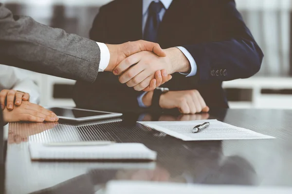 Handshake as successful negotiation ending, close-up. Unknown business people shaking hands after contract signing in modern office