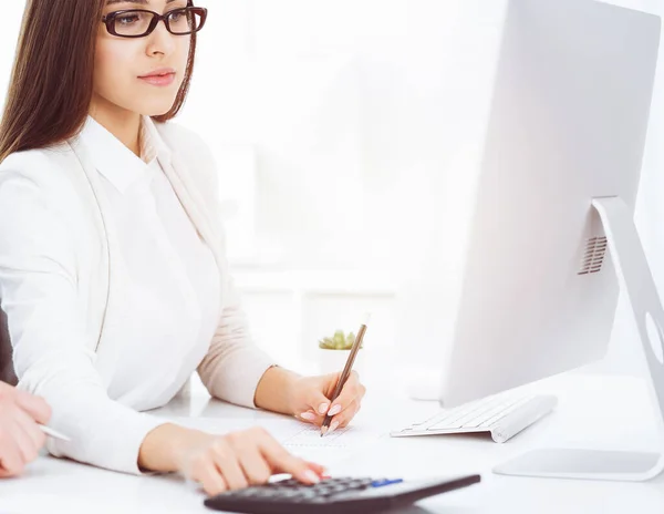 Young business woman and man sitting and working with computer and calculator in sunny office. Tax and audit concepts — Stock Photo, Image