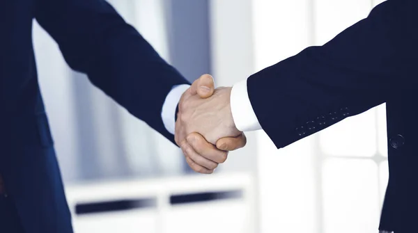 Los empresarios se dan la mano después de firmar el contrato mientras están de pie en una oficina moderna. Trabajo en equipo y concepto de apretón de manos — Foto de Stock