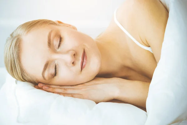 Femme heureuse dormant dans la chambre à coucher confortablement et joyeusement. Se réveiller le matin ensoleillé — Photo