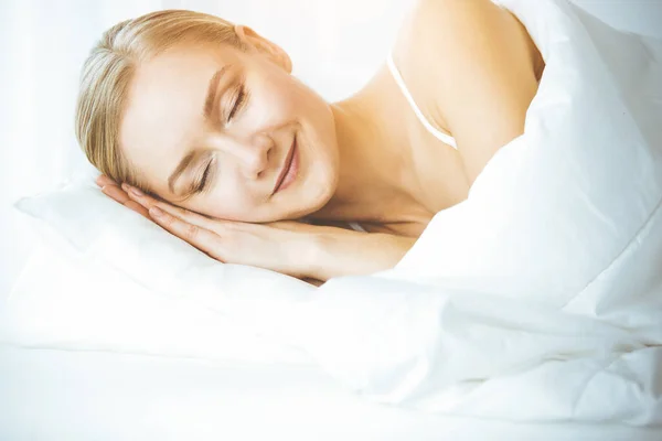 Femme heureuse dormant dans la chambre à coucher confortablement et joyeusement. Se réveiller le matin ensoleillé — Photo