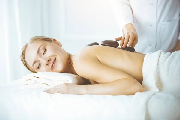 Happy caucasian woman enjoying warm stones procedure with closed eyes. Beauty and Spa salon concept — Foto de Stock