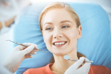 Mutlu kadın dişçi kliniğinde dişçi tarafından muayene ediliyor. Sağlıklı dişler ve ilaçlar, stomatoloji konsepti