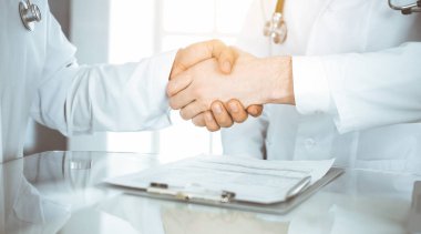 İki doktor hastaların tedavisi konusunda anlaşmak için el sıkışıyor, yakın plan. Tıbbi yardım, tıp konsepti
