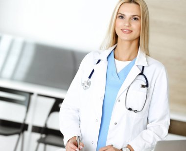 Hastanedeki doktor kadın mesleğinden dolayı heyecanlı ve mutlu. Sarışın doktor ilaç kayıtlarını ve sınav sonuçlarını pano kullanarak kontrol ediyor. Tıp ve sağlık hizmetleri kavramı