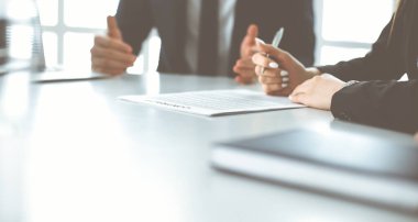 Meçhul iş adamları ve kadınlar modern ofiste oturuyorlar, çalışıyorlar ve sorularını tartışıyorlar.