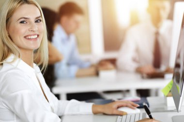 İş yerinde bilgisayarını kullanan sarışın bir iş kadını. Zevk ve başarı için çalışmak