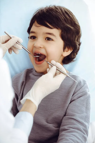 在与牙科医生进行口腔检查的过程中，一个坐在牙椅上张开嘴的阿拉伯小男孩。口腔学概念 — 图库照片