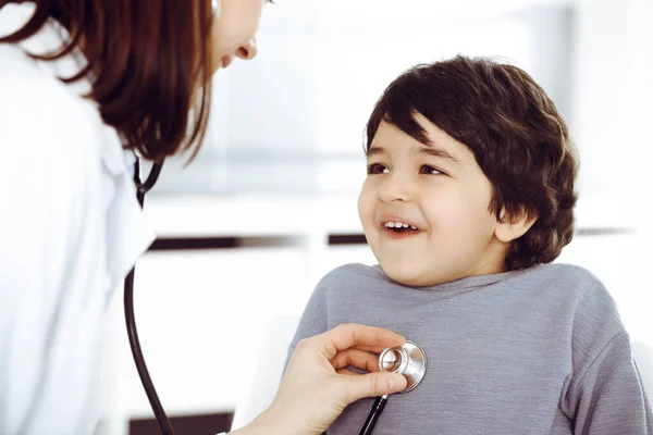 Médico-mujer examinando a un niño paciente por estetoscopio. Lindo chico árabe en la cita con el médico. Concepto de medicina — Foto de Stock