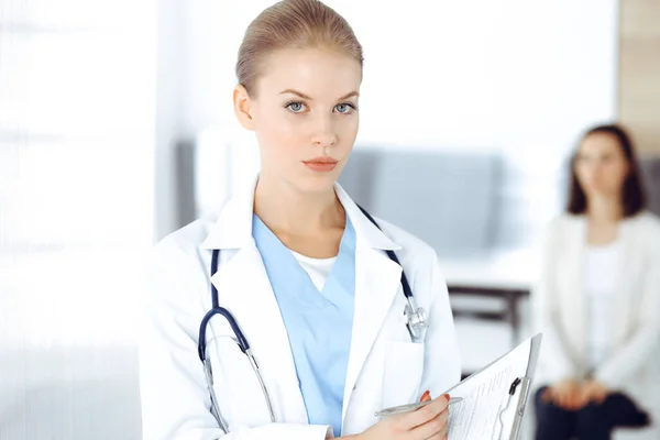 Mulher - médico está usando prancheta para preencher formulário de registro de histórico de medicação na clínica no fundo do paciente. Conceito de medicina — Fotografia de Stock