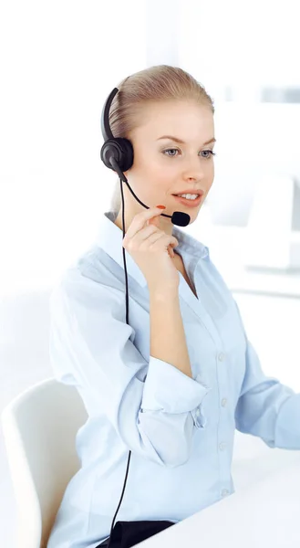 Ξανθιά γυναίκα τηλεφωνητή χρησιμοποιεί υπολογιστή και ακουστικά για τη διαβούλευση των πελατών σε απευθείας σύνδεση. Ομάδα διαφορετικών ανθρώπων που εργάζονται ως επάγγελμα εξυπηρέτησης πελατών. Επιχειρηματική έννοια — Φωτογραφία Αρχείου