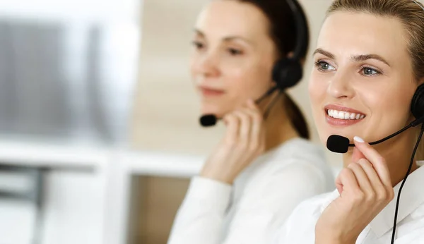 Die blonde Kundendienstmitarbeiterin und ihr Kollege beraten Kunden online per Headset. Callcenter und Geschäftsleute-Konzept — Stockfoto