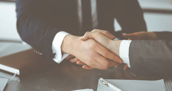 Unknown businessman shaking hands with his colleague or partner above the glass desk in modern office, close-up. Business people group at meeting — Stock Photo, Image