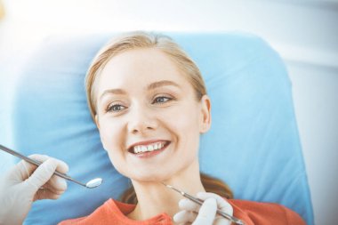 Mutlu kadın dişçi kliniğinde dişçi tarafından muayene ediliyor. Sağlıklı dişler ve ilaçlar, stomatoloji konsepti