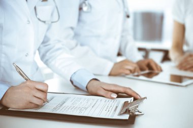 İş yerindeki bilinmeyen kadın doktorlar hastalara danışıyor. Tıbbi belge ya da reçete dolduran kadın doktorlar, yakın çekim. Sağlık hizmeti kavramı