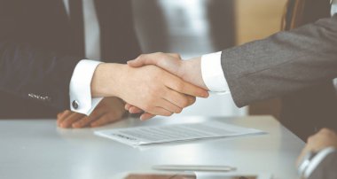 Bilinmeyen işadamı, modern ofiste iş arkadaşı ya da ortağıyla el sıkışıyor. Toplantıda iş adamları grubu