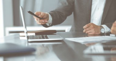 Bilinmeyen iş adamları ve kadınlar oturmuş, dizüstü bilgisayarlarını kullanıyorlar ve modern ofiste buluşmada soruları tartışıyorlar, yakın plan.