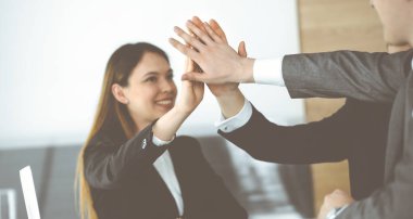 Bilinmeyen iş adamları modern ofiste el ele tutuşuyor. İş adamları ve kadınlar elleriyle bir takım olarak daire çiziyorlar, yakın plan.