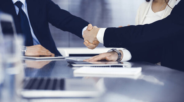 Business people shaking hands after contract signing in modern office. Teamwork and handshake concept