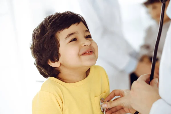 Mujer-médico examinando a un niño paciente por estetoscopio. Lindo chico árabe en la cita con el médico. Medicina ayuda concepto — Foto de Stock