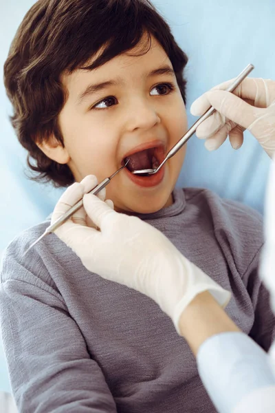 Pequeño chico árabe sentado en la silla dental con la boca abierta durante la revisión oral con el médico dentista. Concepto de estomatología — Foto de Stock