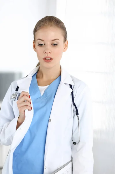Mujer - médico de pie en la clínica. Médico en el trabajo, retrato de estudio. Concepto de medicina y salud —  Fotos de Stock