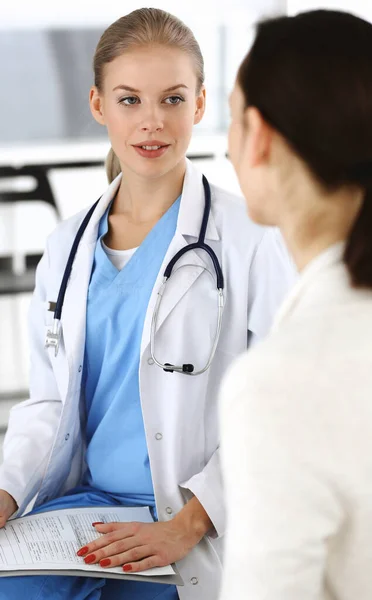 Женщина - врач консультируется с пациенткой при использовании буфера обмена и истории болезни. Концепция медицины — стоковое фото