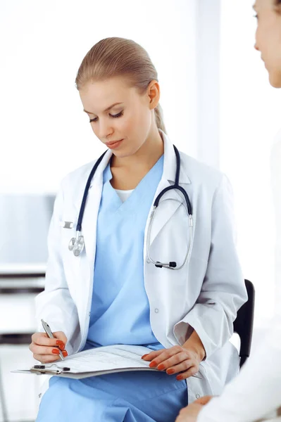 Woman - doctor consults her female patient while using clipboard and medication history record. Medicine concept