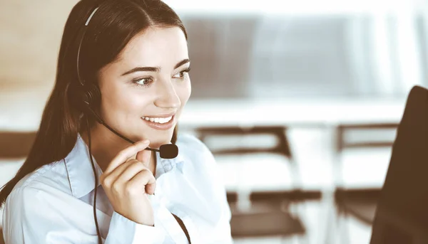 Morena representante de servicio al cliente femenino en un auricular está consultando a los clientes en línea. Centro de llamadas y concepto de gente de negocios — Foto de Stock