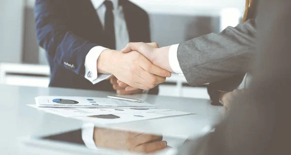 Unknown businessman shaking hands with his colleague or partner above the glass desk in modern office, close-up. Business people group at meeting — Stock Photo, Image