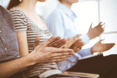 İş adamları toplantı ya da konferansta el çırpıyor. Modern beyaz ofisteki bir grup tanınmayan iş adamı ve kadın. Başarı takım çalışması, kurumsal koçluk ve alkış konsepti