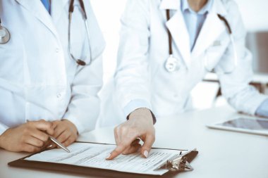 İş yerindeki bilinmeyen kadın doktorlar, arka planda hastaları var. Hastane resepsiyonunda beklerken tıbbi belgeleri dolduran kadın doktorlar, yakın plan. Sağlık hizmeti kavramı