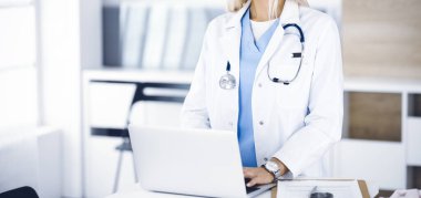 Laptop bilgisayarı kullanan kimliği belirsiz bir kadın doktor, yakın plan. Klinikteki kadın doktor. Tıp konsepti