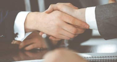 Bilinmeyen işadamı, modern ofiste iş arkadaşı ya da ortağıyla el sıkışıyor. Toplantıda iş adamları grubu