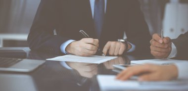 Bilinmeyen iş adamları modern ofiste birlikte çalışıyorlar, yakın plan. İş adamı ve kadın iş arkadaşları veya avukatlarıyla pazarlıkta sözleşmeyi tartışıyor