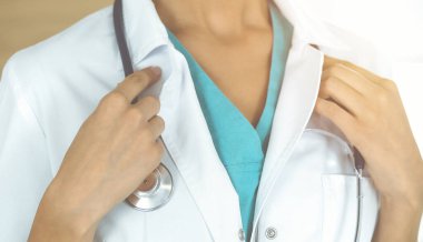 Güneşli klinikte steteskopla dikilen kimliği belirsiz kadın doktor, yakın plan.