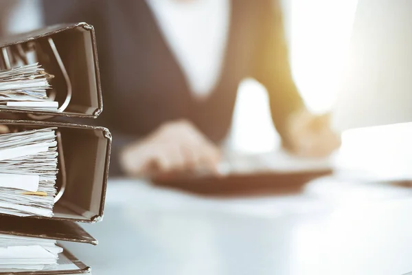 Binders with papers are waiting to be processed by business woman or bookkeeper working at the desk in office back in blur. Audit and tax concept — Stock Photo, Image