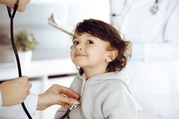 Mujer-médico examinando a un niño paciente por estetoscopio. Lindo niño árabe en la cita con el médico. Concepto de medicina —  Fotos de Stock