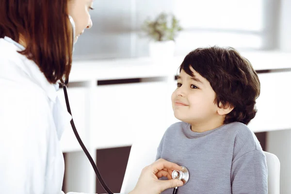 Médico-mujer examinando a un niño paciente por estetoscopio. Lindo chico árabe en la cita con el médico. Concepto de medicina — Foto de Stock