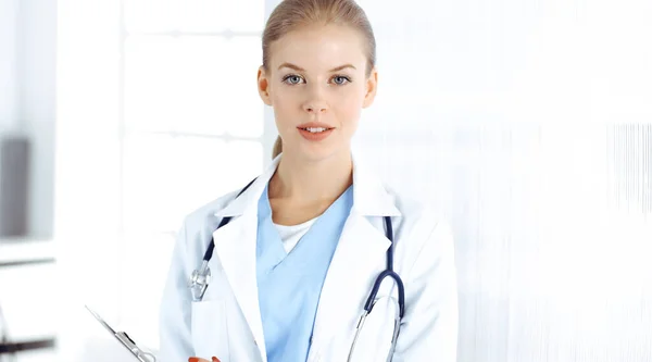 Mulher - médico em pé na clínica. Médico a trabalhar, retrato de estúdio. Conceito de medicina e cuidados de saúde — Fotografia de Stock