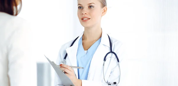 Woman - doctor consults her female patient while using clipboard and medication history record. Medicine concept