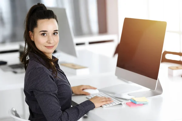 İş kadını, güneşli ofiste bilgisayar kullanıyor. Zevk ve başarı için çalışmak